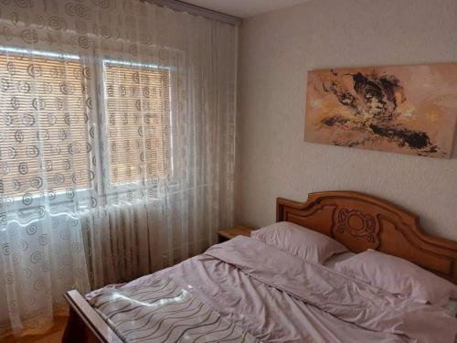 1 dormitorio con cama y ventana en Comfortable apartment close to the city center, en Pristina