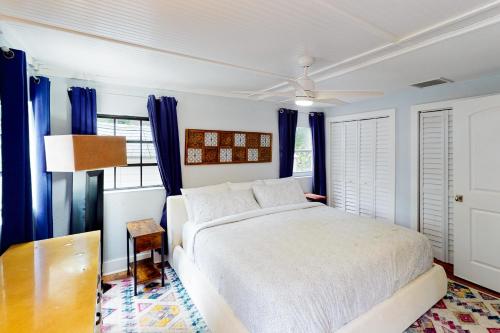 a bedroom with a white bed and blue curtains at Turquoise Turtle Manor in Tavernier