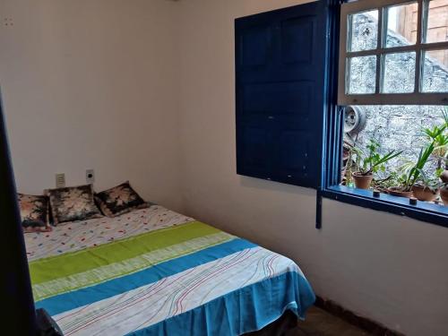 a bedroom with a bed and a window with plants at Casa da tranquilidade in Ouro Preto