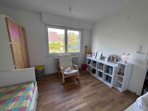 a bedroom with a bed and a chair and a window at Maison familiale proche Strasbourg in Illkirch-Graffenstaden