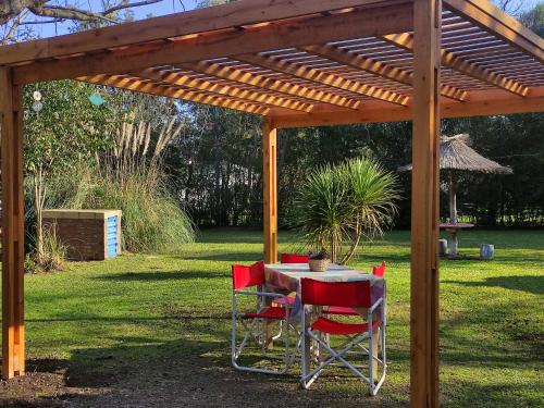 a table and chairs under a wooden pergola at Studios La Bella Vida en Escobar in Belén de Escobar