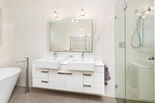 een witte badkamer met 2 wastafels en een spiegel bij Vue De La Mer Gerroa in Gerroa
