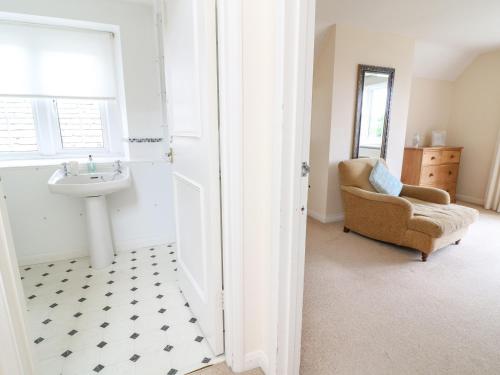 a bathroom with a sink and a chair at Home Farm 16 in Witney