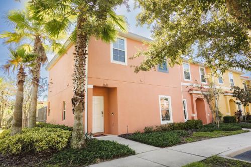a pink building with palm trees in front of it at Townhouse Near Disney Sleeps 10 Guests & Dog-Friendly! in Kissimmee