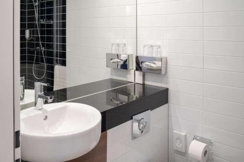 a white bathroom with a sink and a mirror at prizeotel Affoltern Am Albis in Affoltern