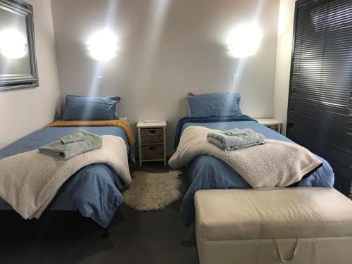 two twin beds in a room with blue pillows at Sandy Toes Holiday Home Orewa in Orewa