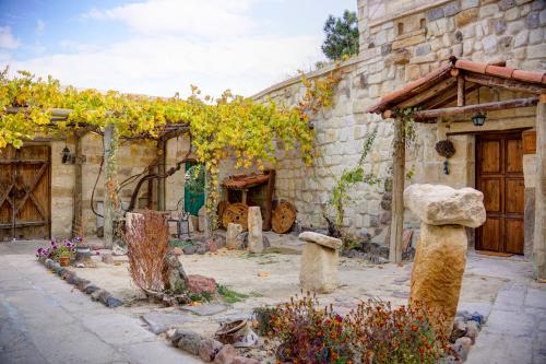 a stone building with a bunch of trees in a courtyard at Gibos Cave Hotel in Urgup