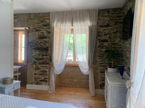 a bedroom with a window with white curtains at Quintal do Grémio in Torre de Moncorvo
