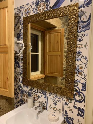 uma casa de banho com um espelho e um lavatório em Quintal do Grémio em Torre de Moncorvo