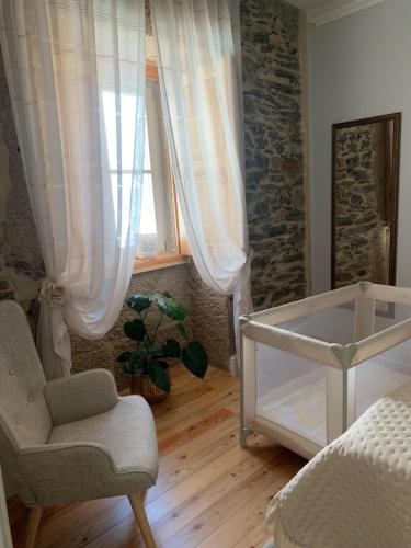 a room with a bed and a chair and a window at Quintal do Grémio in Torre de Moncorvo