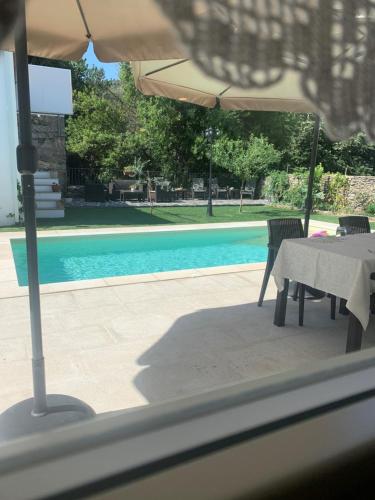 uma mesa e cadeiras com um guarda-sol ao lado de uma piscina em Quintal do Grémio em Torre de Moncorvo