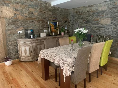 a dining room with a table with chairs and a stone wall at Quintal do Grémio in Torre de Moncorvo
