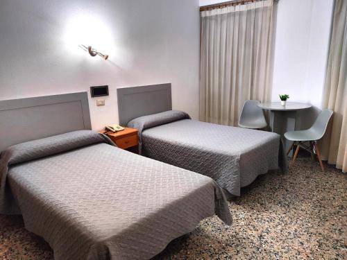 Habitación de hotel con 2 camas y mesa en Hotel Cogullada, en Zaragoza