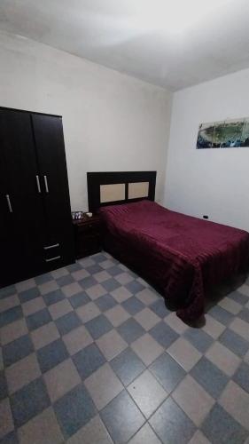 1 dormitorio con cama roja y suelo de baldosa en Hostel la abuela en La Unión