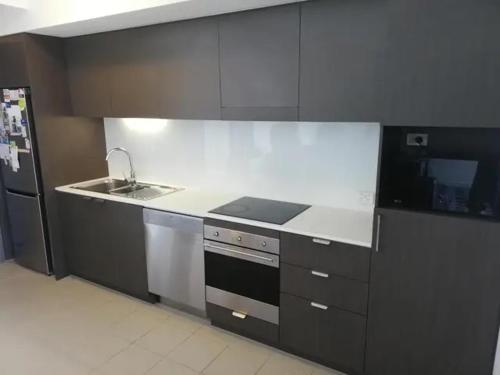 a kitchen with a stove and a refrigerator at Bedroom & Private Bathroom in Modern Inner Brisbane Apartment in Brisbane