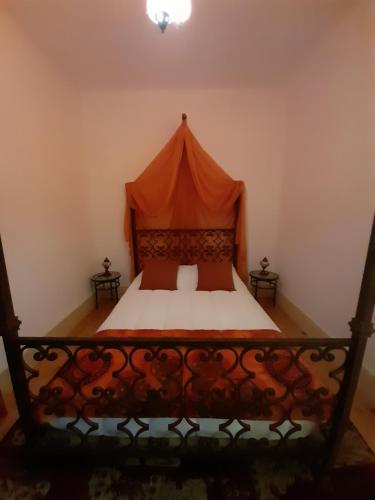 a bedroom with a bed with an orange canopy at Casa da Varanda in Carreço
