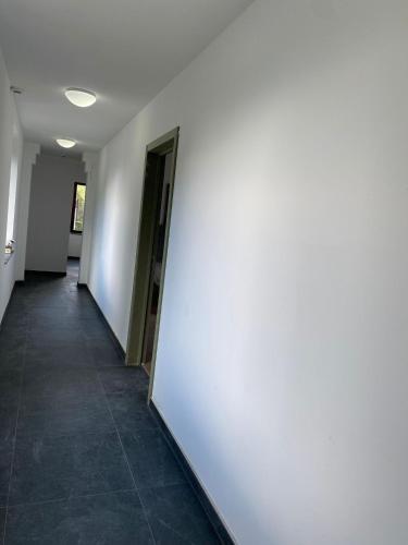 a hallway with a white wall and a tile floor at Ardenne in Spa