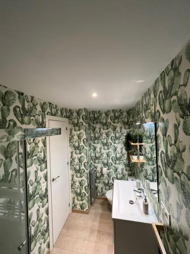 baño con papel pintado verde y blanco y lavabo en Apartamento Cué, en Gijón