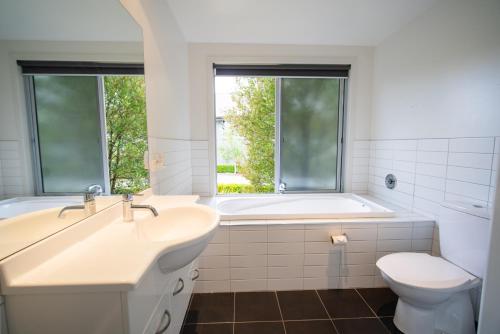 a bathroom with a tub and a sink and a toilet at Southland Sounds - Te Anau Holiday Home in Te Anau