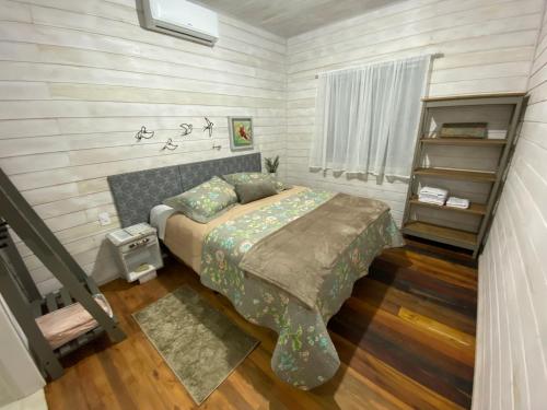 a bedroom with a bed and a book shelf at Chalé Terra Luni in Urubici