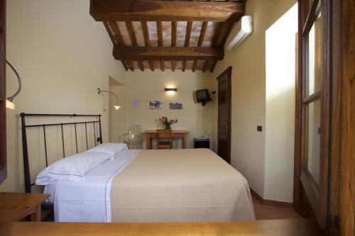 1 dormitorio con cama blanca y mesa en Bio Agriturismo Il Torrione, en Saturnia