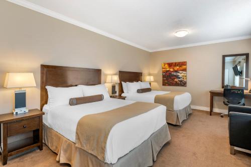 a hotel room with two beds and a chair at Regent Hotel Revelstoke in Revelstoke