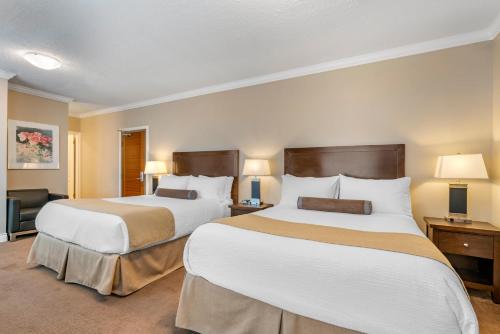 two beds in a hotel room with two lamps at Regent Hotel Revelstoke in Revelstoke