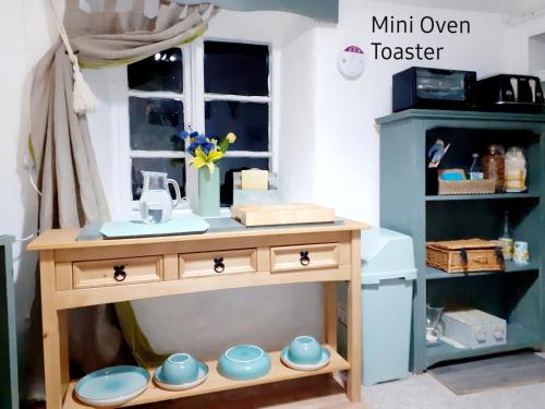 a small wooden table with bowls and plates on it at Higher Barton Guest room in Martock