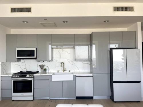 a white kitchen with a sink and a refrigerator at Luxury Highrise Condo Downtown LA in Los Angeles