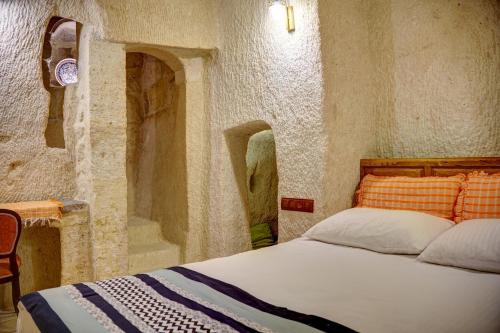 a bedroom with a bed in a stone wall at Gibos Cave Hotel in Urgup