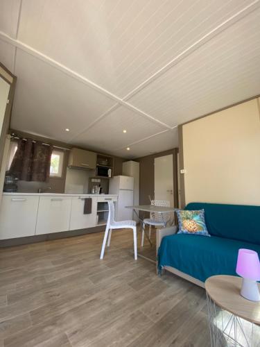 ein Wohnzimmer mit einem blauen Sofa und einer Küche in der Unterkunft Les chalets des Îles in Borgo