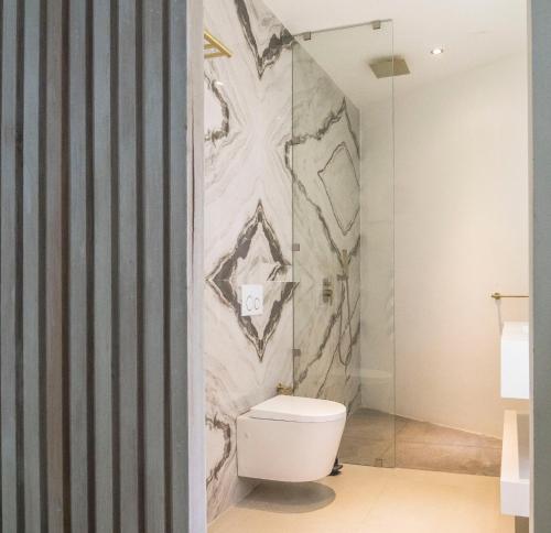 a bathroom with a toilet and a marble wall at KUNUK- Walk to Hermosa beach in Santa Teresa Beach