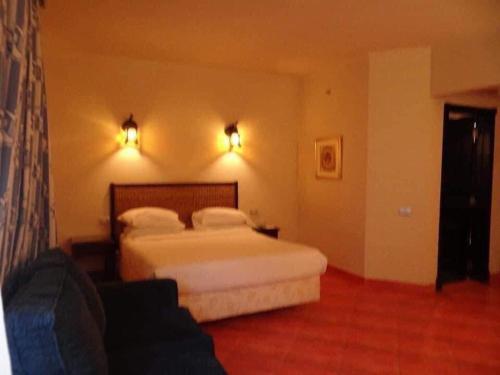 um quarto de hotel com uma cama e um sofá em فندق و سبا بورتو مارينا em El Alamein