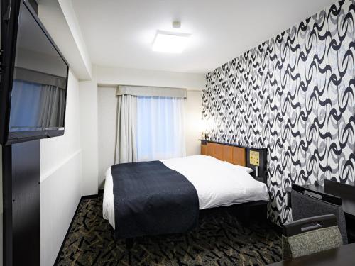 a hotel room with a bed and a tv at APA Hotel Sapporo Odori Ekimae Minami in Sapporo