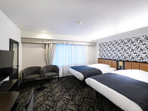 a hotel room with two beds and a television at APA Hotel Sapporo Odori Ekimae Minami in Sapporo
