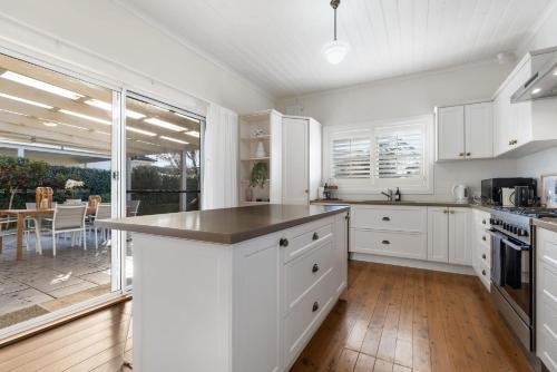 cocina con armarios blancos y ventana grande en Sampson Cottage - Historic Charm en Orange