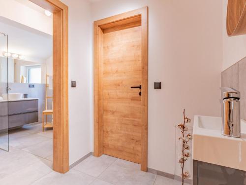 La salle de bains est pourvue d'un lavabo et d'une porte en bois. dans l'établissement Tirola Stadl Vroni Hansl, à Hopfgarten im Brixental
