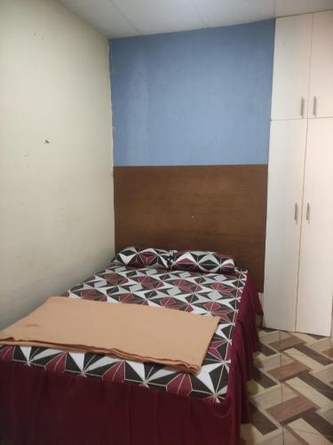 um pequeno quarto com uma cama com colcha em Blue House - cerca del consulado americano em Guayaquil