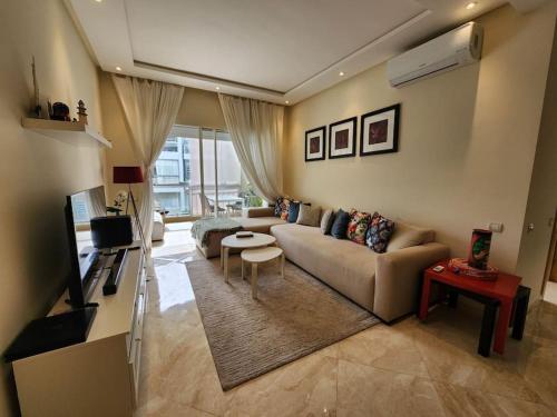 a living room with a couch and a tv at Casabay Sidi Rahal plage vue sur piscine et mer in Sidi Rahal