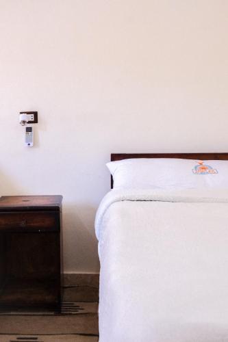 a bedroom with a white bed and a wooden table at Al-Manara Hostel Siwa Oasis in Siwa