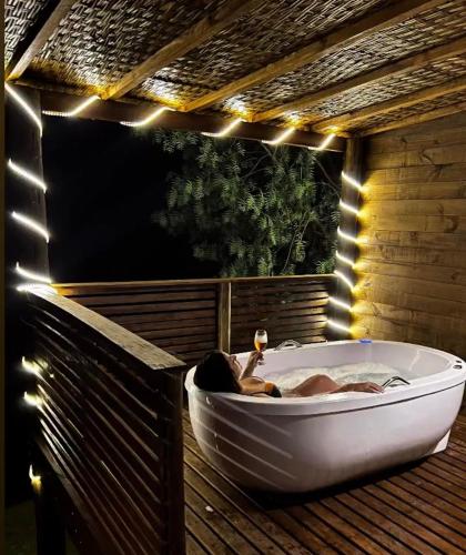 a woman in a bath tub on a deck with lights at Chalé do Lago super Luxo in Cunha