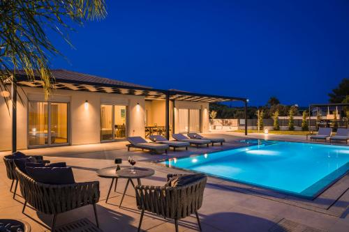 a pool with chairs and a table next to a house at AL MARE VILLAS in Lixouri