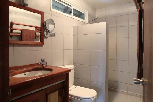 y baño con aseo, lavabo y espejo. en Raira Lagon en Avatoru