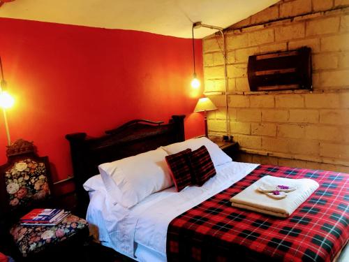 a bedroom with a bed with a red wall at Mi Casa es tu Casa Inn in Chiquinquirá