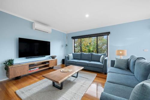 a living room with blue furniture and a flat screen tv at Cowrie Central Townhouse in Torquay