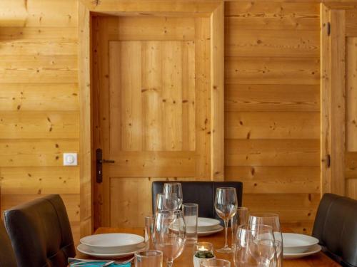 a wooden table with wine glasses on it at Relaxing Poolside Alpine Apt in Vallorcine