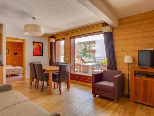 a living room with a table and chairs and a television at Relaxing Poolside Alpine Apt in Vallorcine