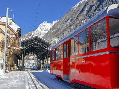 a red train parked at a train station in the snow at Relaxing Poolside Alpine Apt in Vallorcine