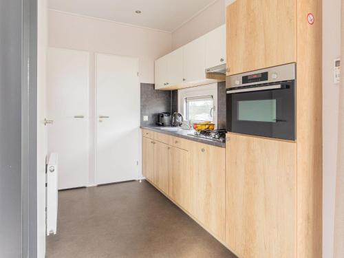 a kitchen with wooden cabinets and a microwave at Chalet by Beach and Harbor with Terrace in Well
