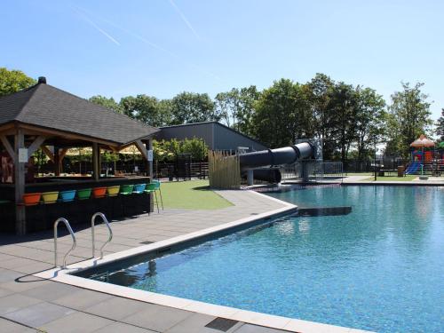 une piscine avec un toboggan et une aire de jeux dans l'établissement Modern chalet with a dishwasher, in a holiday park at a recreational lake, à Lathum
